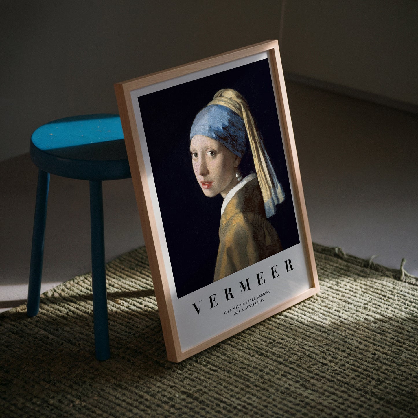 Art print of Vermeer's "Girl with a Pearl Earring," featuring a young woman with a blue and gold headscarf and a pearl earring, set against a dark background.